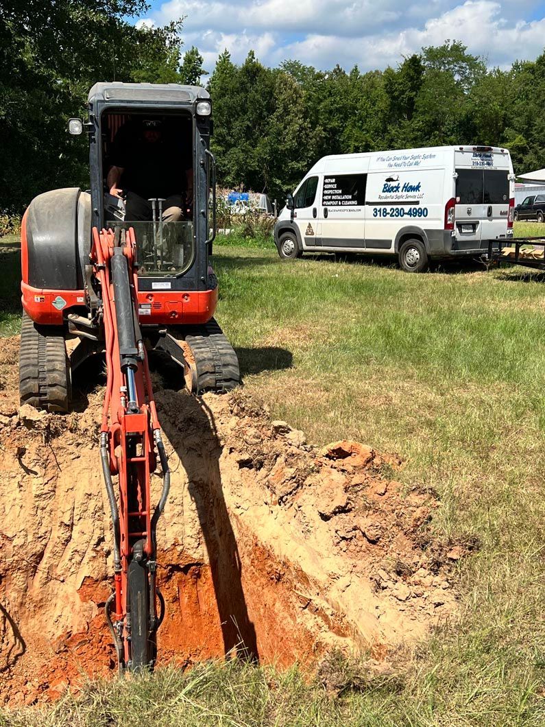 Orange excavator digging a trench in a grassy area with a white work van in the background.