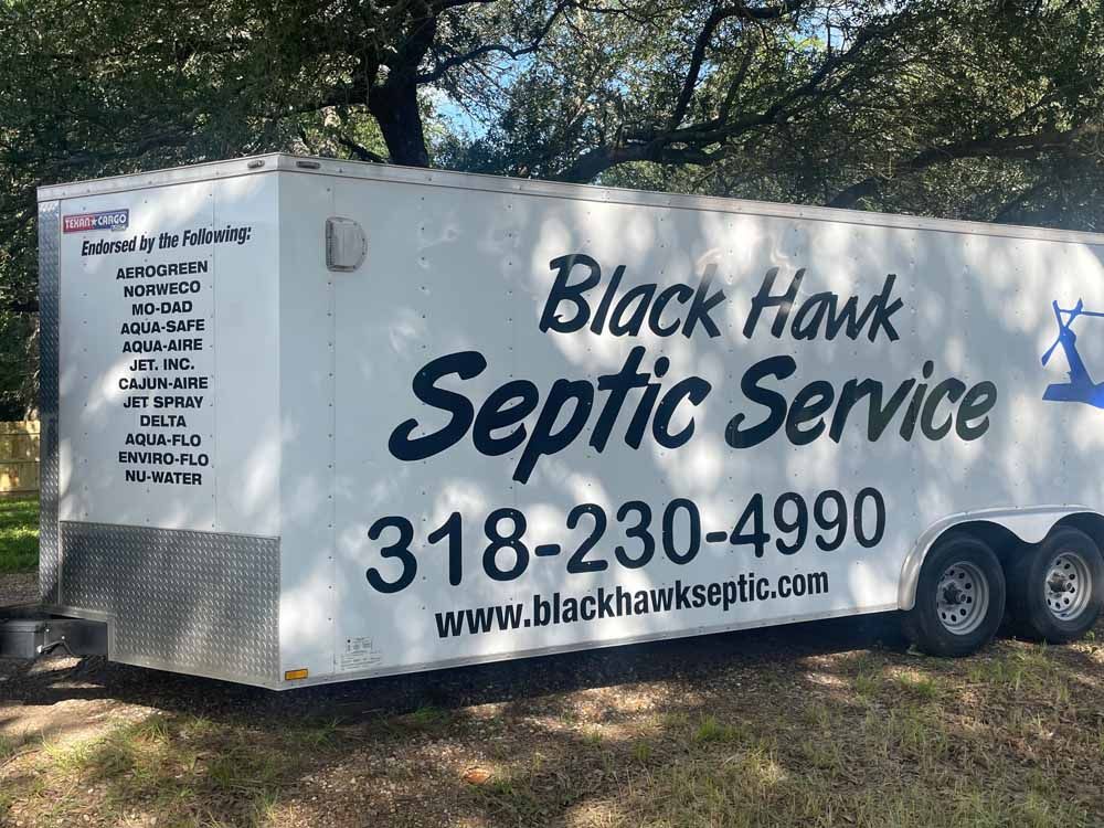 White trailer for Black Hawk Septic Service, phone number and website on the side.