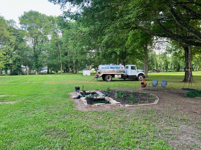 White water truck parked on a grassy lawn; hose in use.