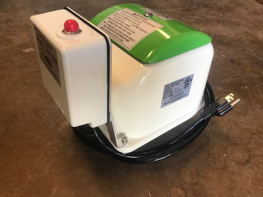 White and green electric motor with a red button on a white box.