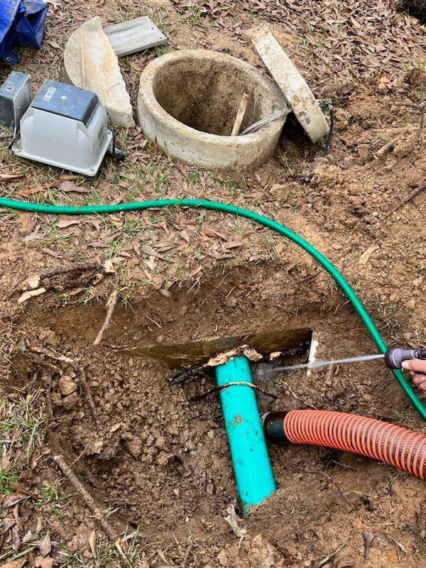Open septic tank components during maintenance. Green hose, pump, and pipe visible.