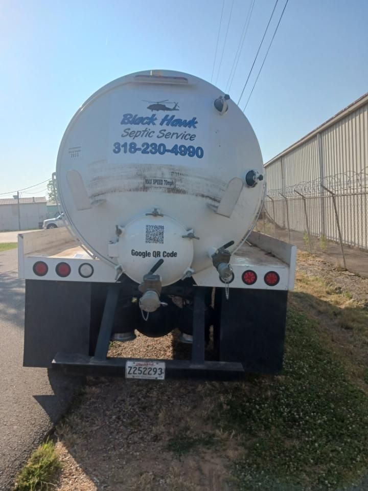 Back of a white Black Hawk Septic Service truck with a phone number and QR code. Parked on a road.