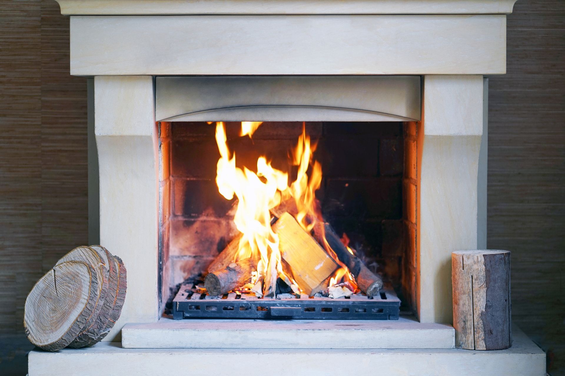 Lit stone fireplace, with burning wood inside, and wooden discs next to it.