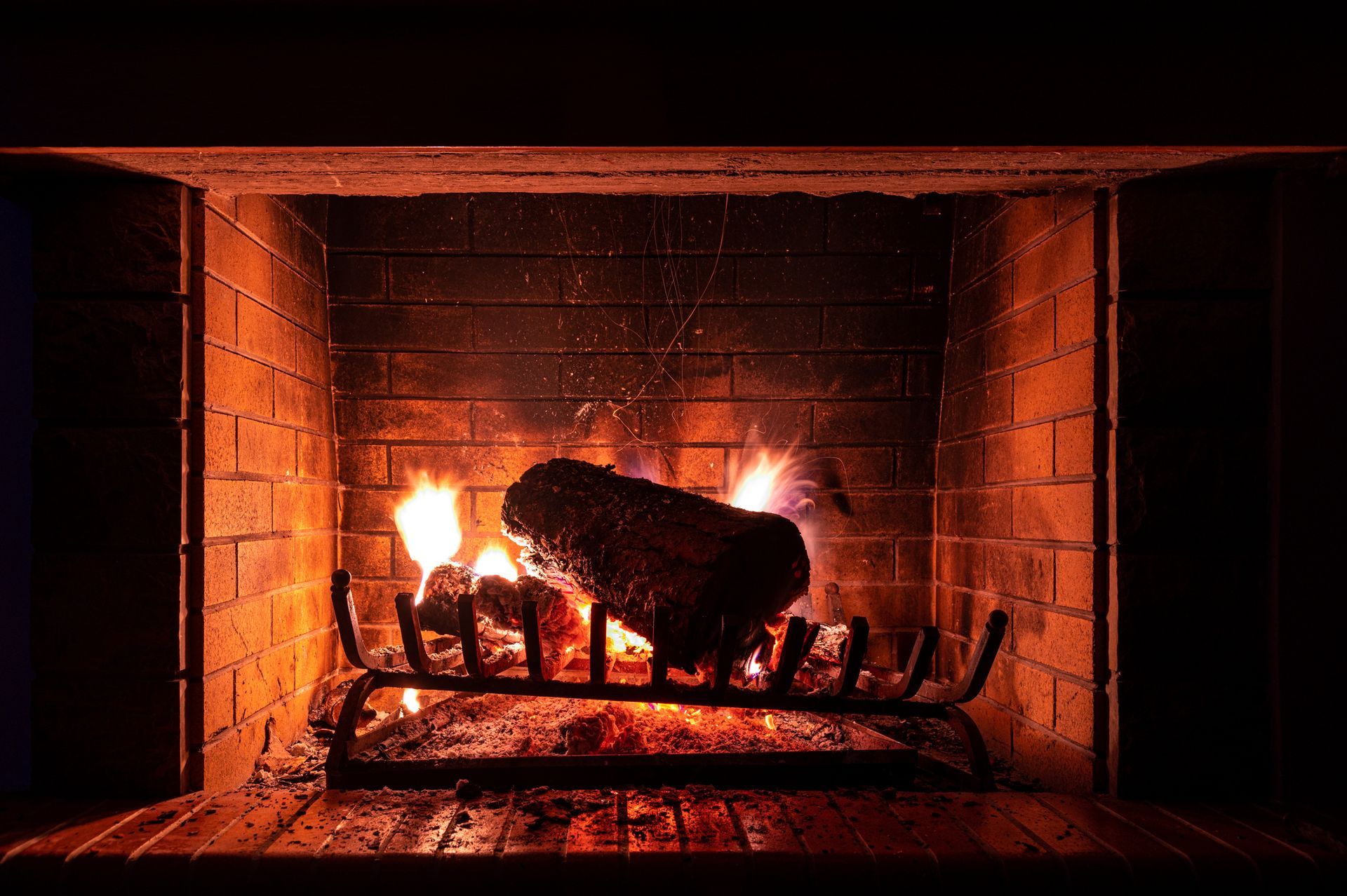 A lit fireplace with burning logs and flames.