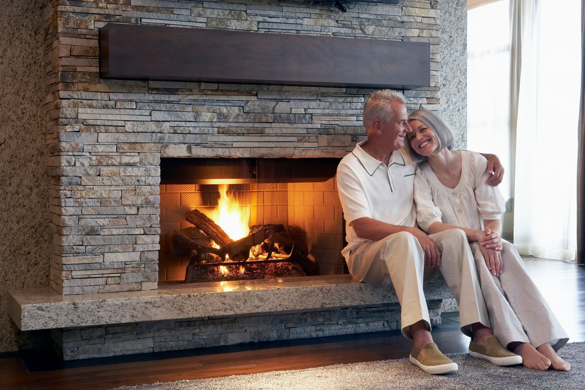 Two people sitting by a fireplace with a fire burning. Two people sitting by a fireplace with a fire burning.