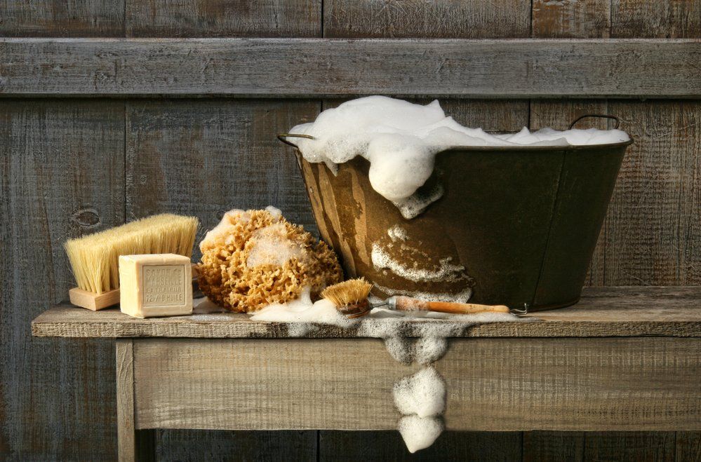 bucket full of soapy water with sponges outside of an old barn
