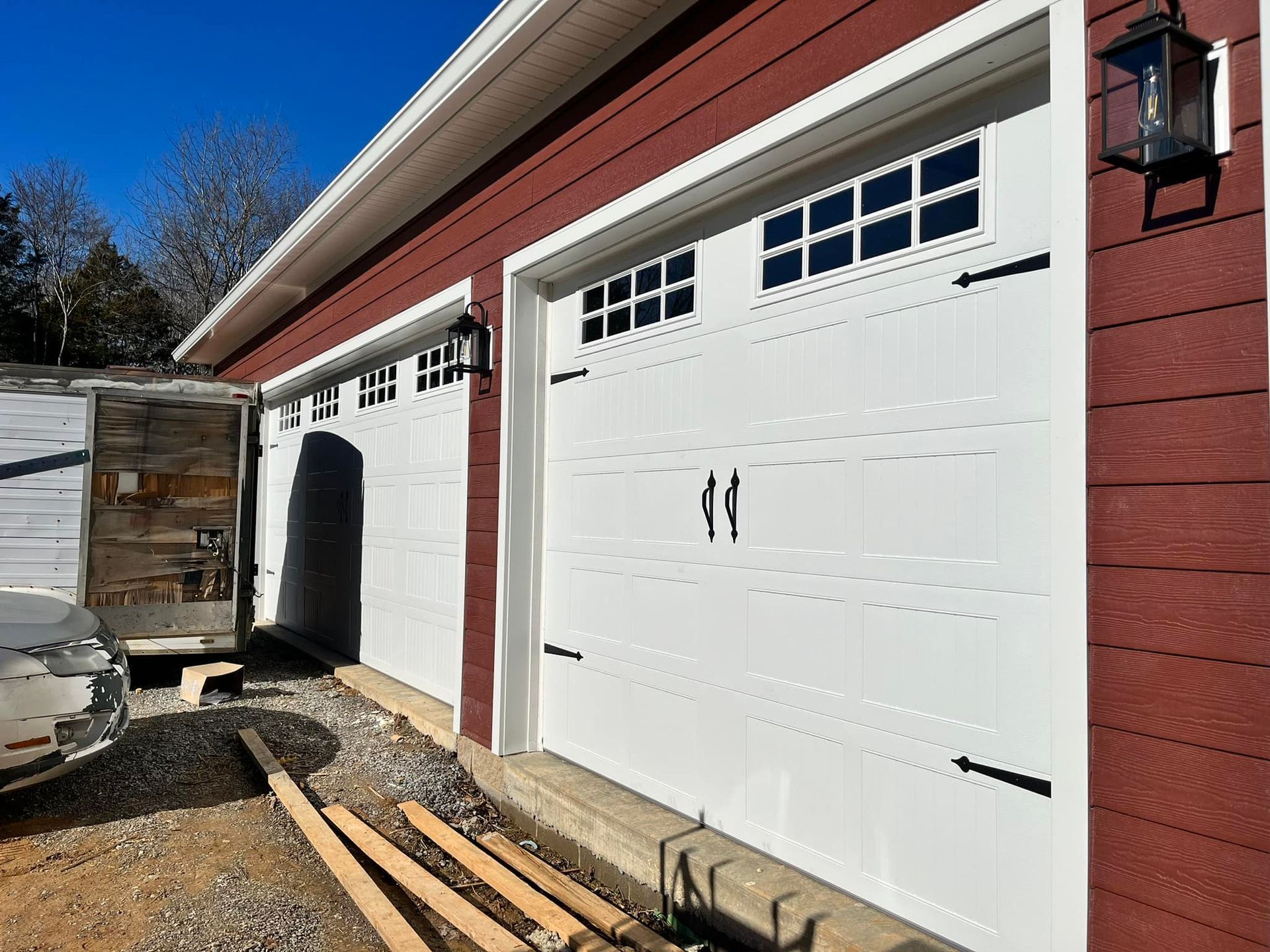 White garage doors with black accents on a red building.