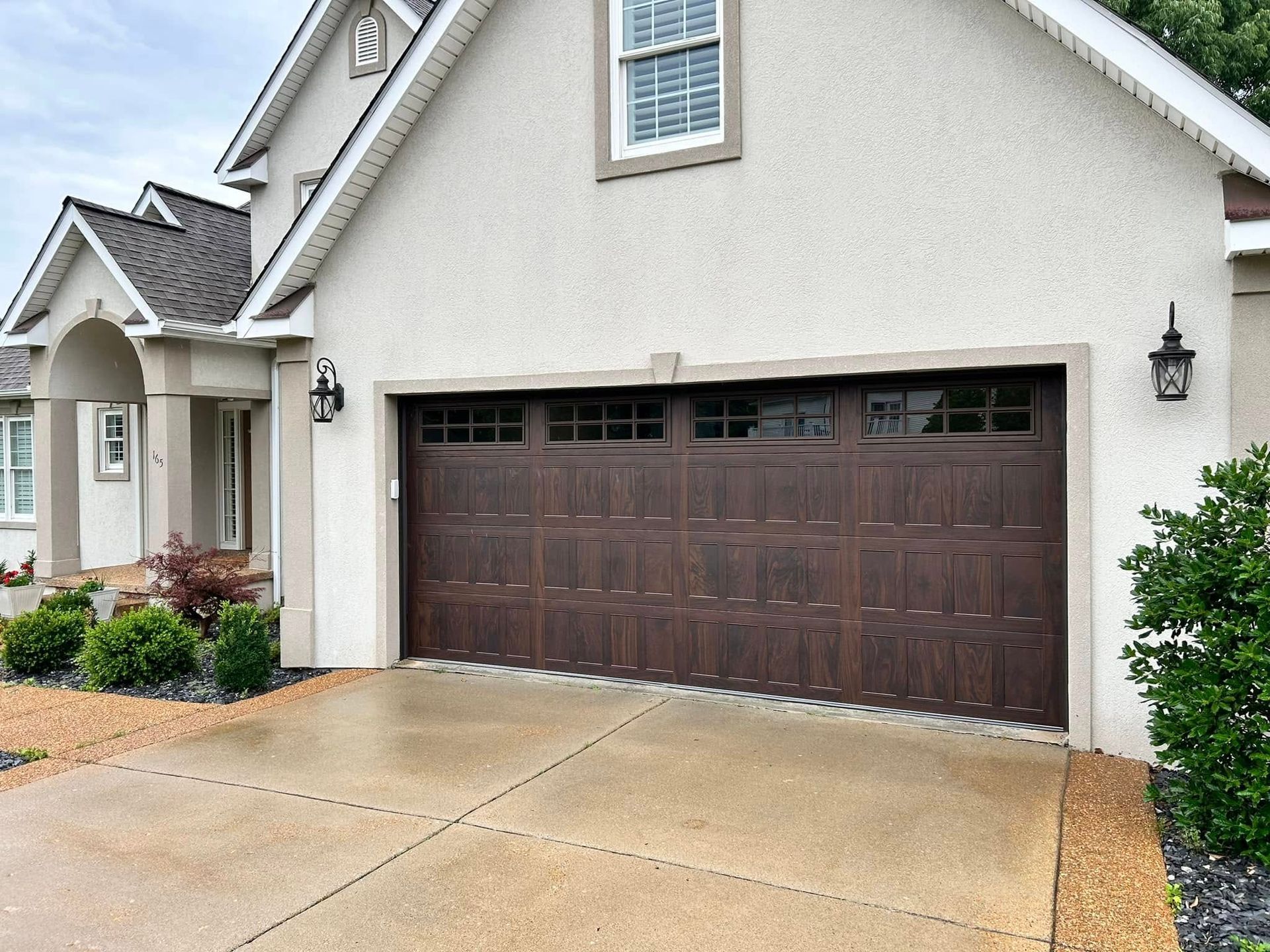 Brown garage door on a light stucco house with a concrete driveway.