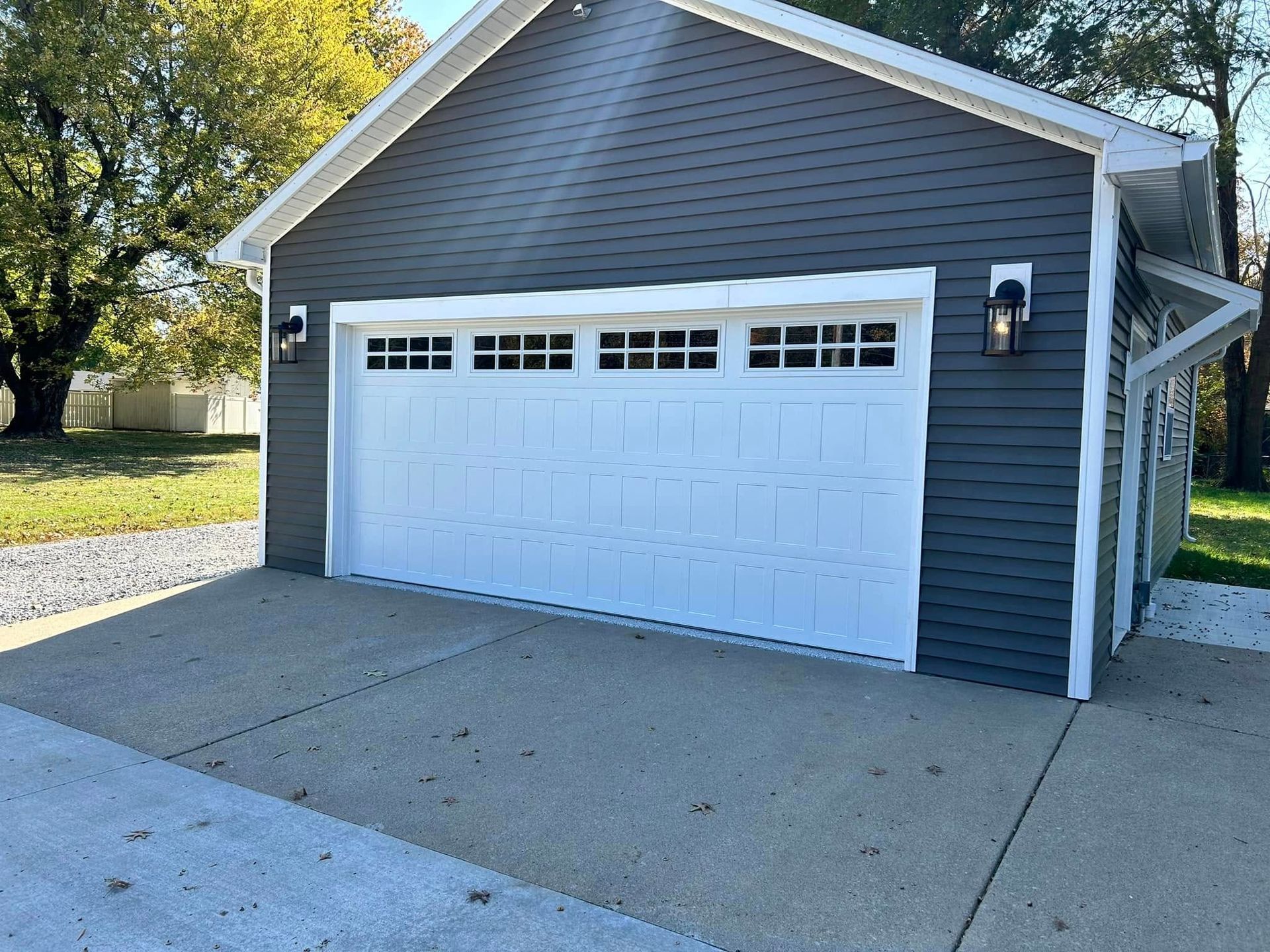 Gray detached garage with white trim and door, set on a concrete pad.