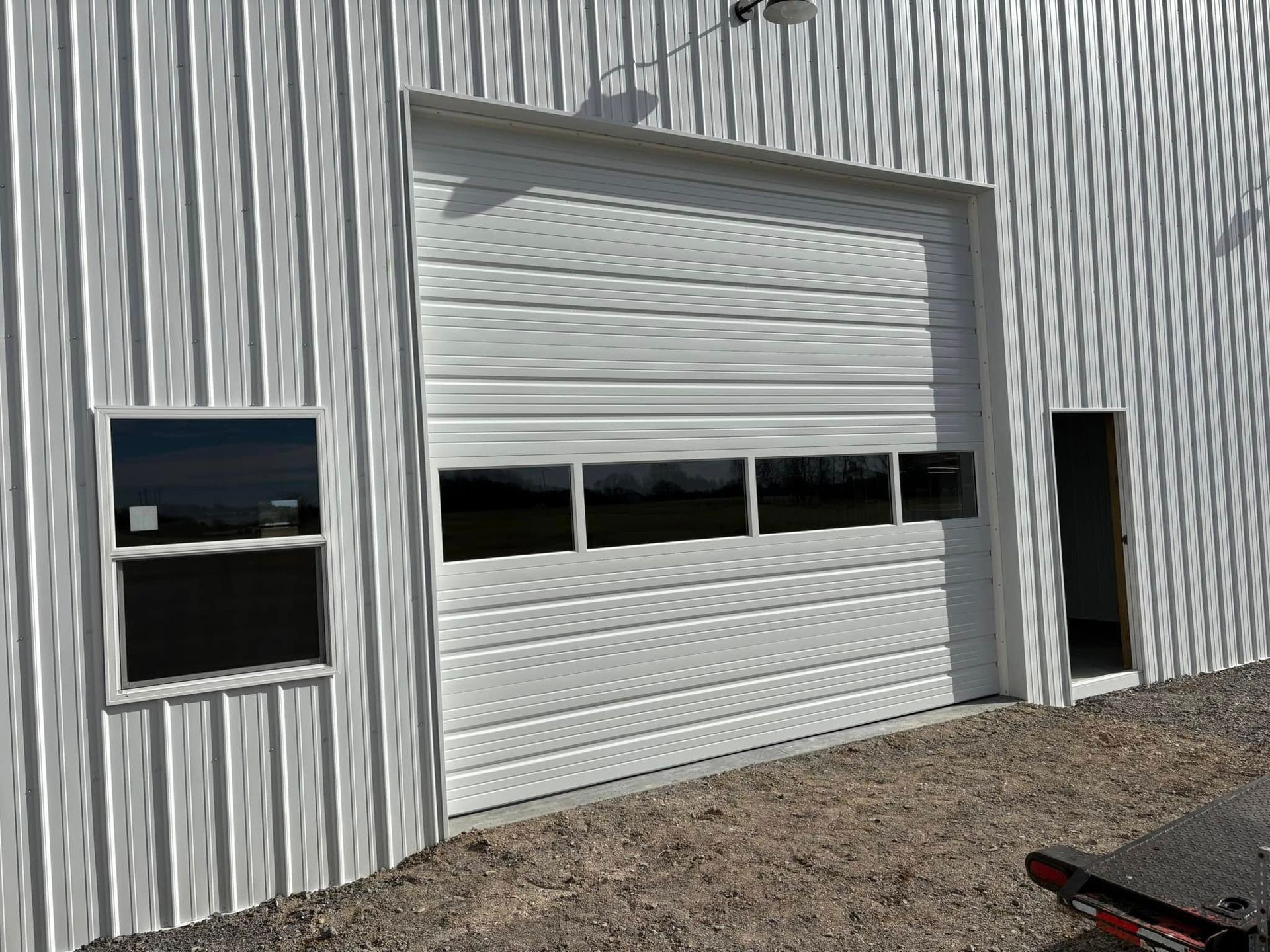 White metal building with a closed garage door and a small window.