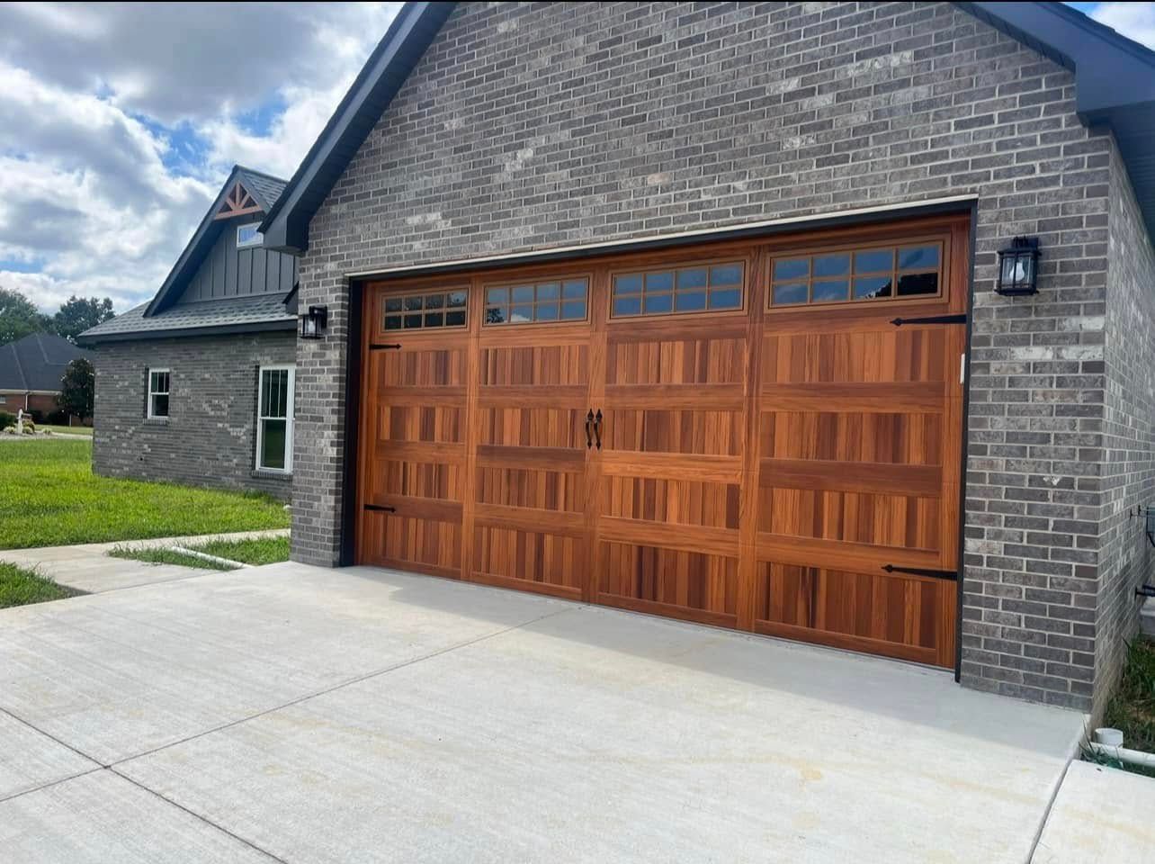 Wooden garage door on a brick building with a concrete driveway.