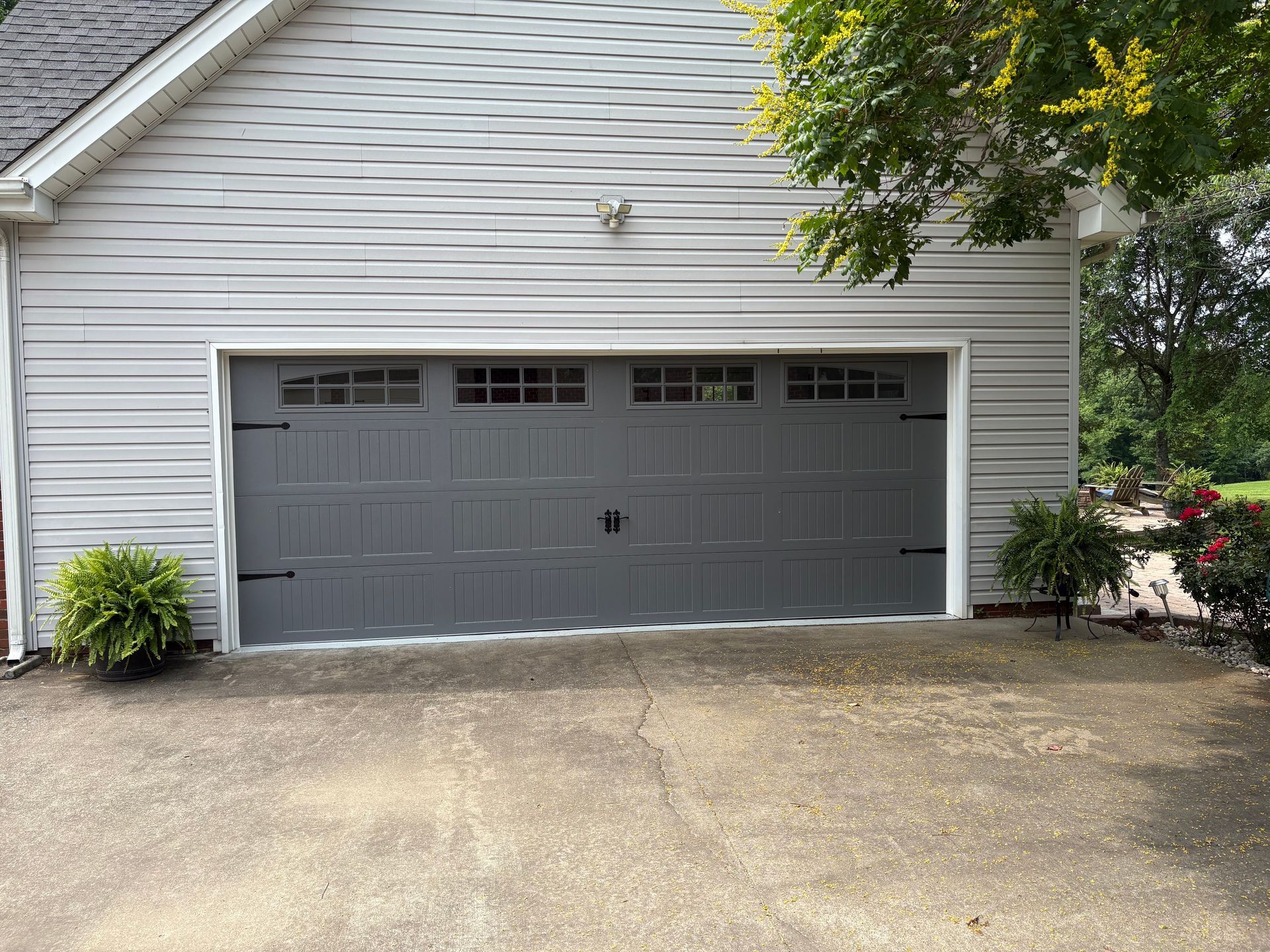 Gray garage with matching door, white trim, and light gray siding. A paved driveway leads up to it.