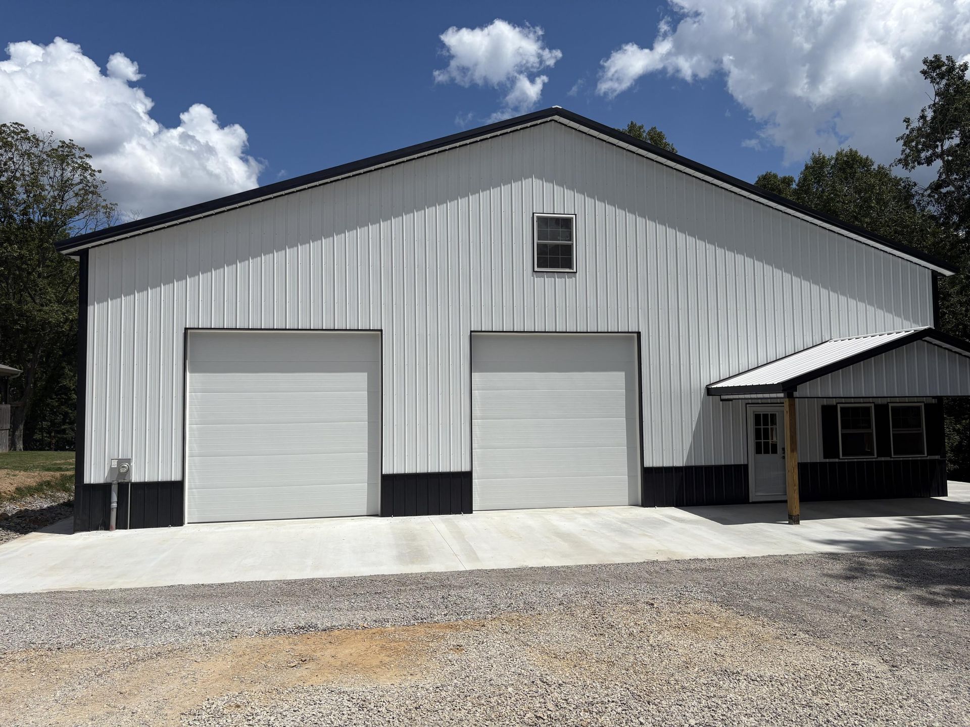 White metal building with two garage doors, an awning, and concrete drive.