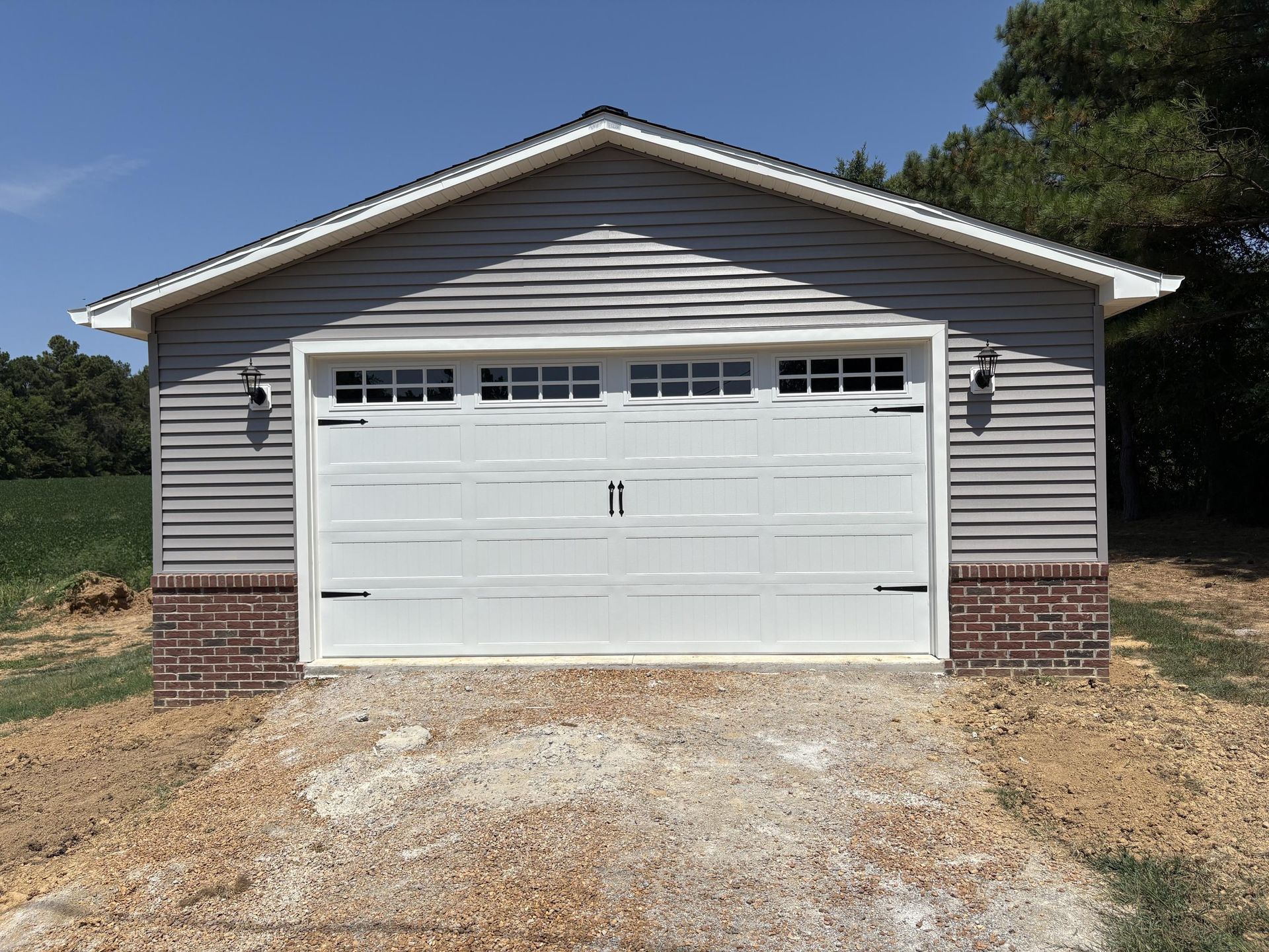 Gray garage with white door and brick base, outdoors.