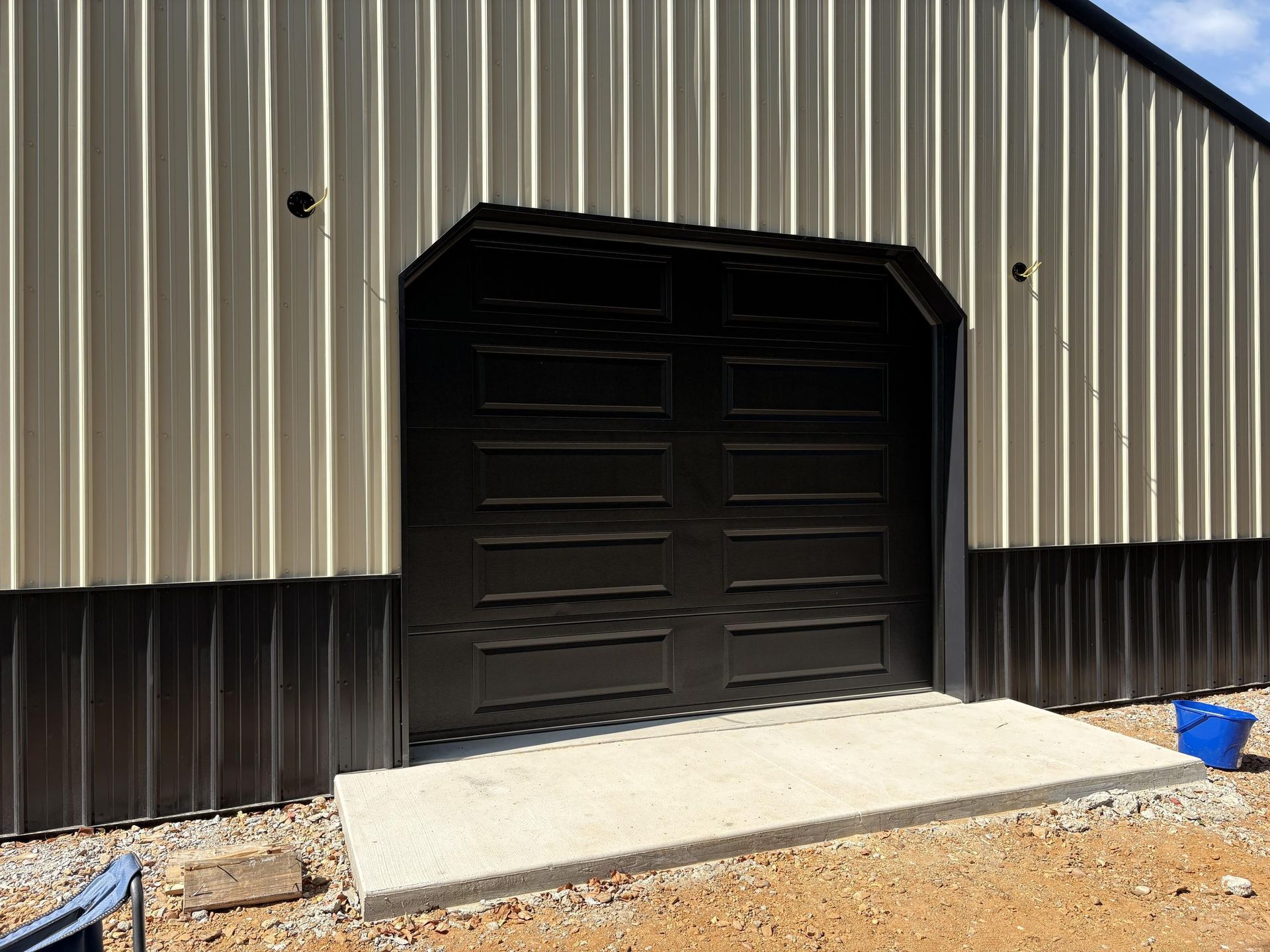 Tan and black building with a dark closed door and a concrete entryway.