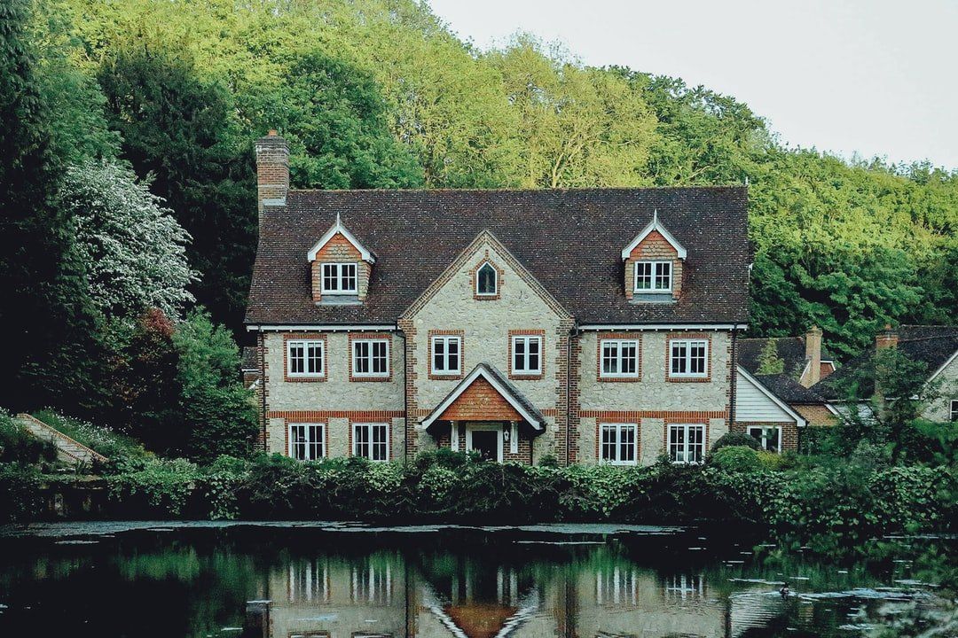 A large estate is sitting next to a lake in the middle of a forest.