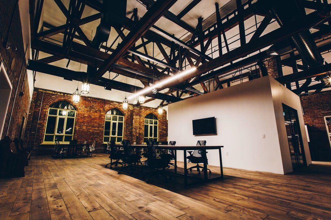 A large empty room with a wooden floor and a brick wall.