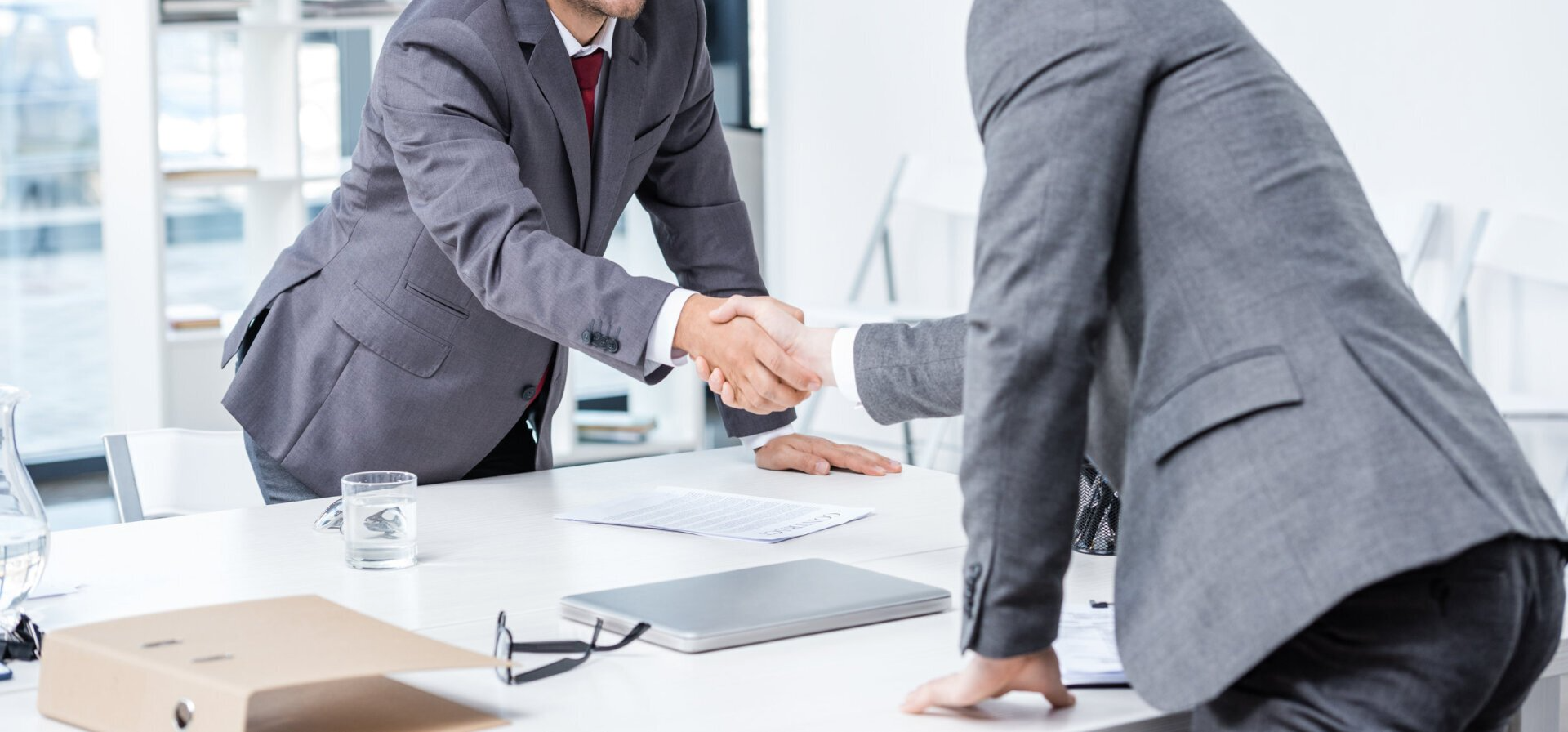 Two businessmen are shaking hands while sitting at a table, representing the topic of real estate law.