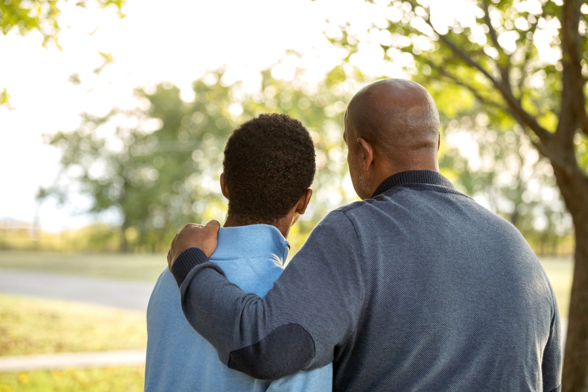 A man and a boy are mourning next to each other in a park.