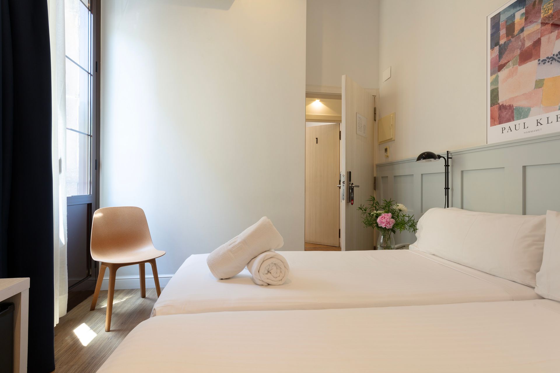 Un dormitorio con cama, silla y ventana.