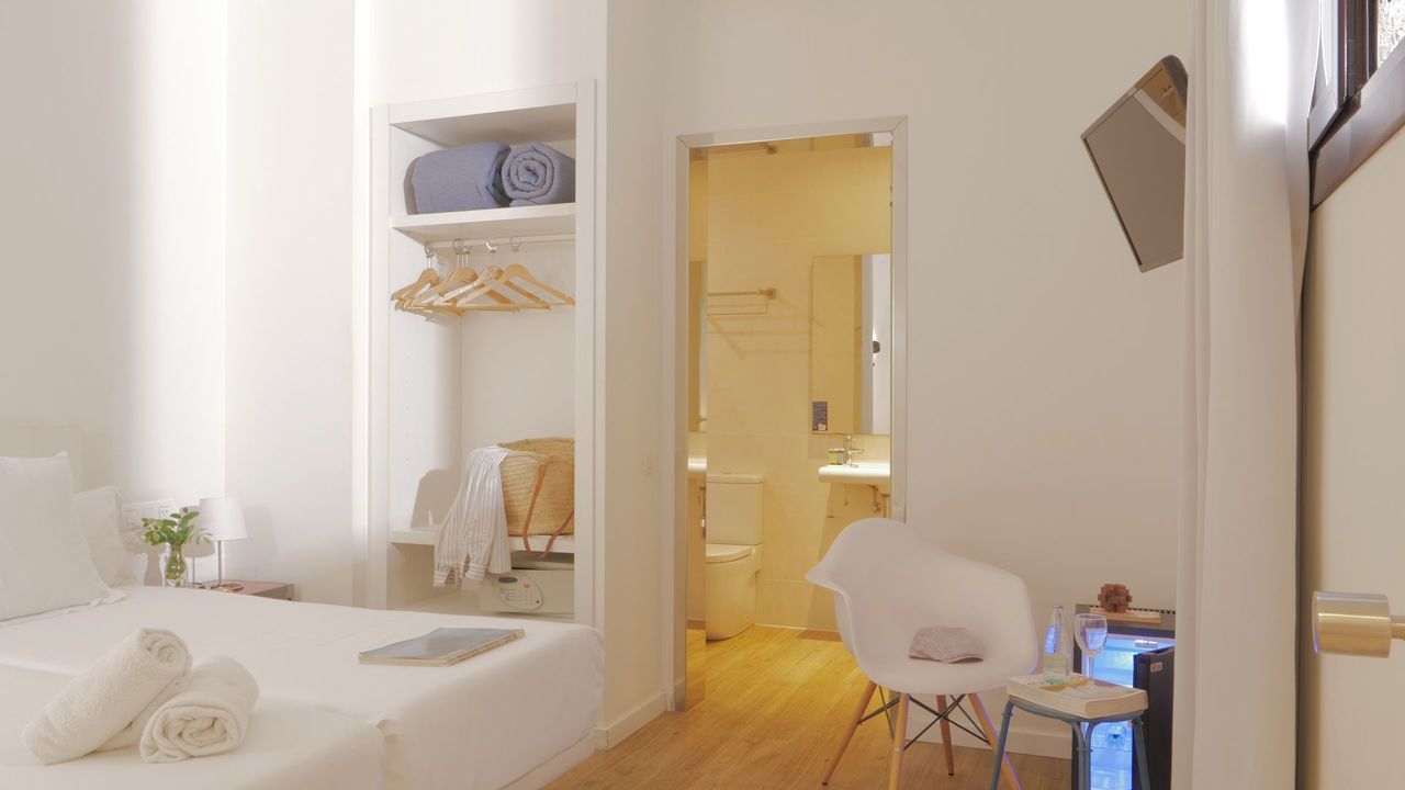 Un dormitorio con una cama, silla, mesa y un baño.