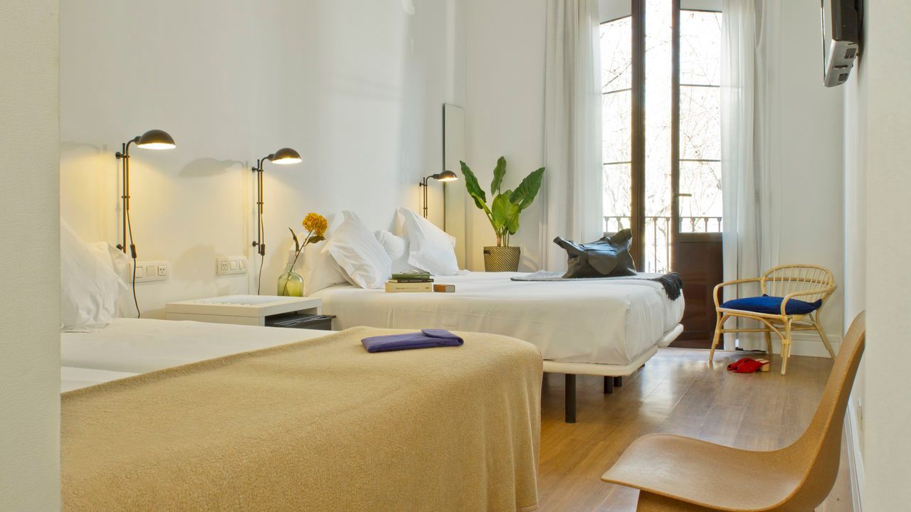 Una habitación de hotel con tres camas y una silla.