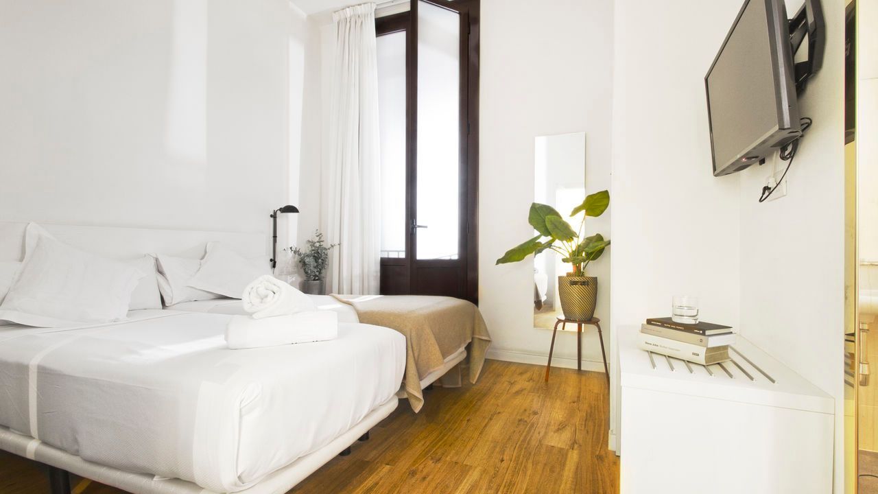 Un dormitorio con dos camas y un televisor de pantalla plana en la pared.