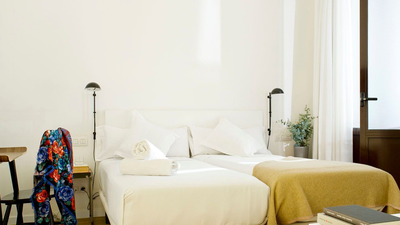 Un dormitorio con dos camas, una mesa y una silla.