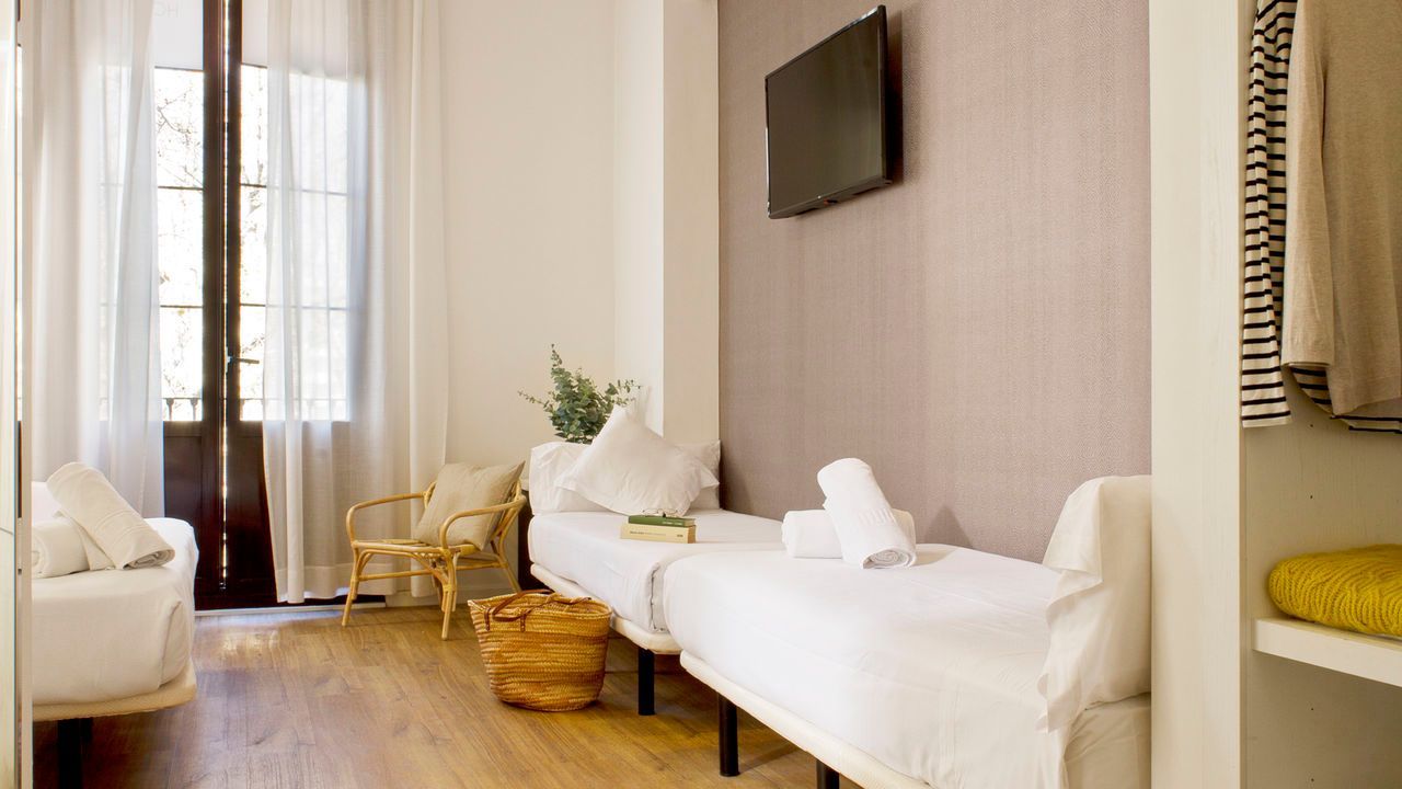 Un dormitorio con dos camas y una televisión en la pared.