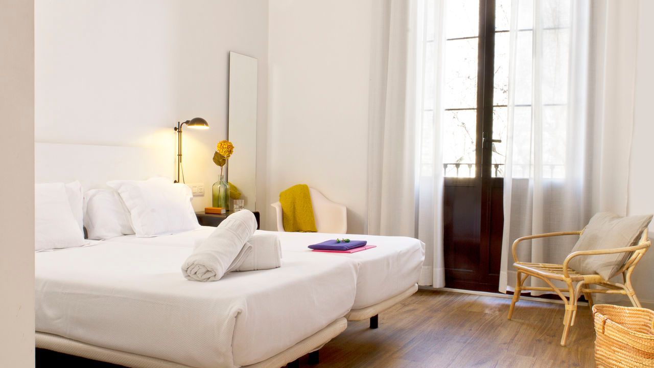 Una habitación de hotel con dos camas, una silla y una ventana.