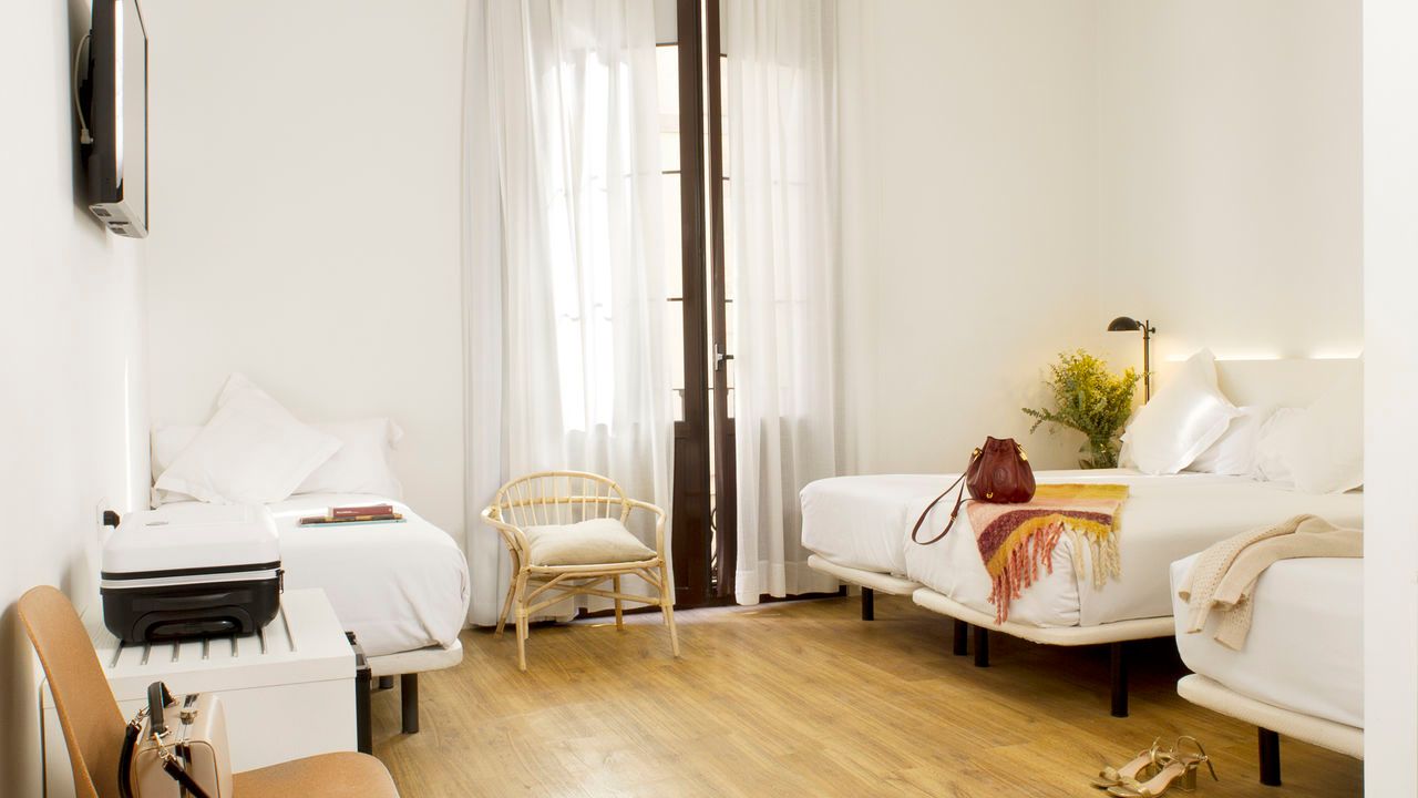 Una habitación de hotel con dos camas, una silla y una televisión.