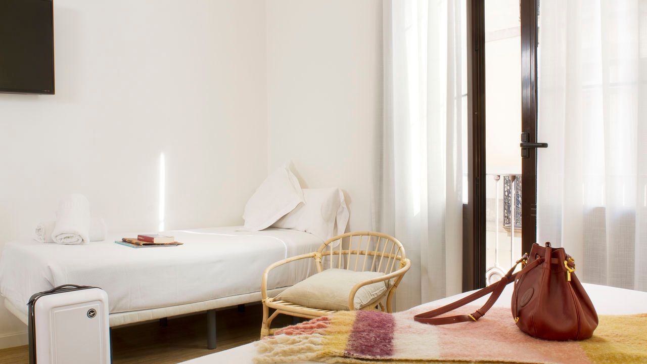 Una habitación de hotel con dos camas, una silla, una maleta y un bolso.