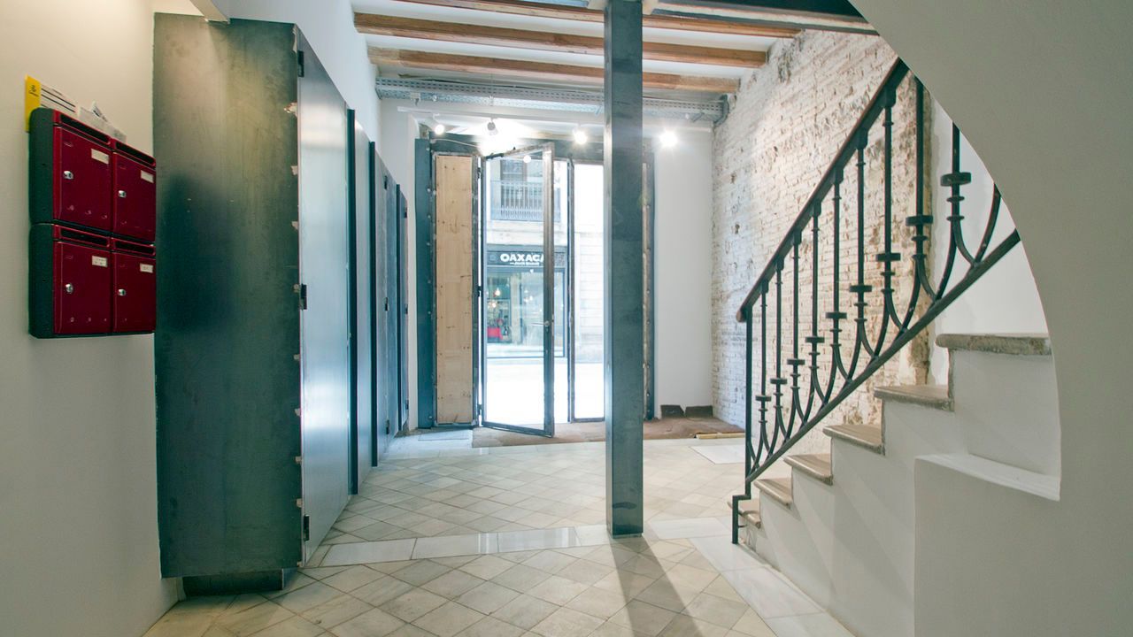 Un pasillo con escaleras y buzones en la pared.