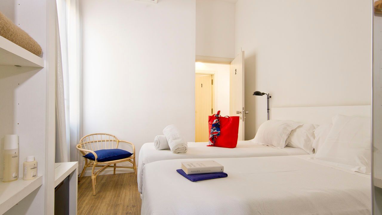 Un dormitorio con dos camas, una silla y una ventana.