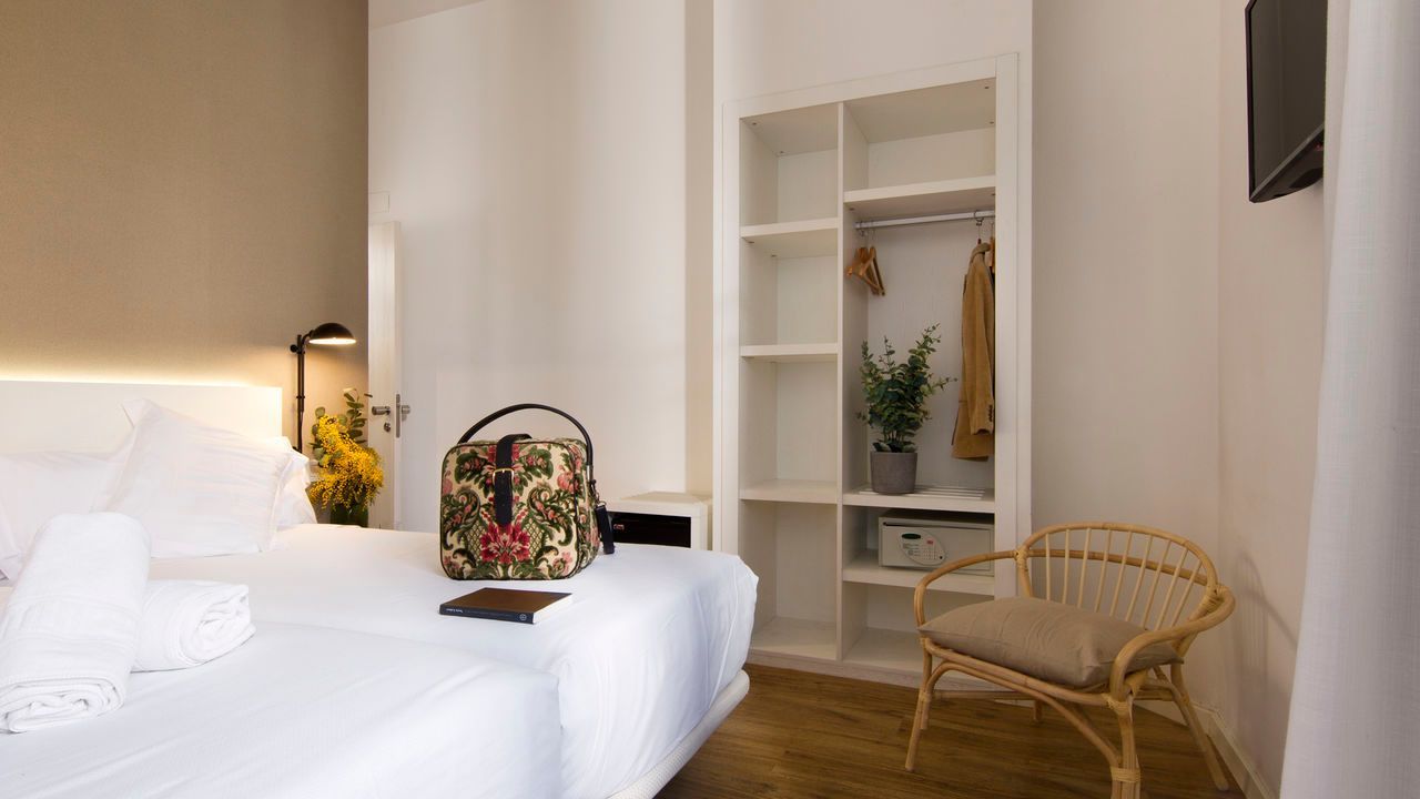 Un dormitorio con cama, silla, armario y televisión.