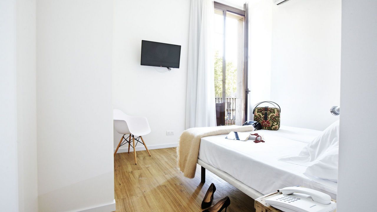 Un dormitorio con una cama y un televisor en la pared.