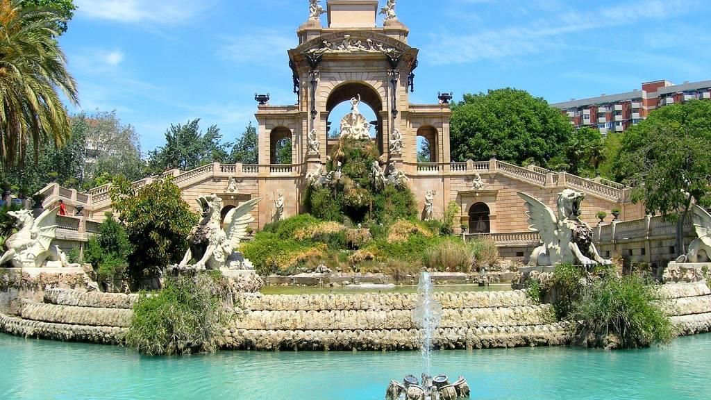 Un edificio grande con una fuente enfrente en un parque.