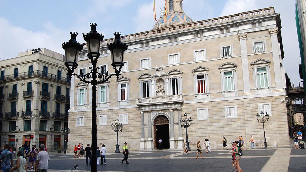 Un grupo de personas camina frente a un gran edificio.