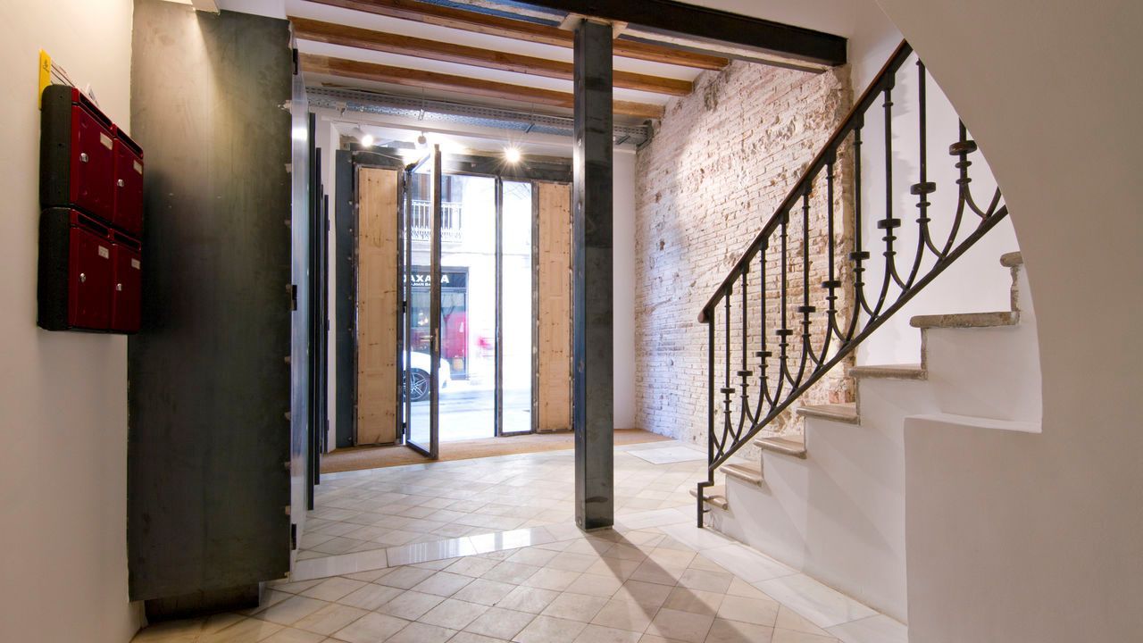 Un pasillo con escaleras y barandilla de hierro forjado.