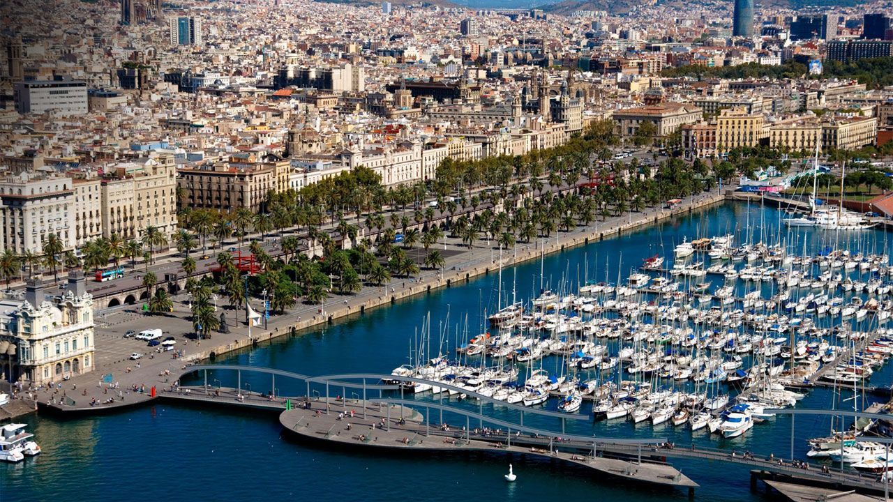 Una vista aérea de un puerto con barcos atracados y una ciudad al fondo.