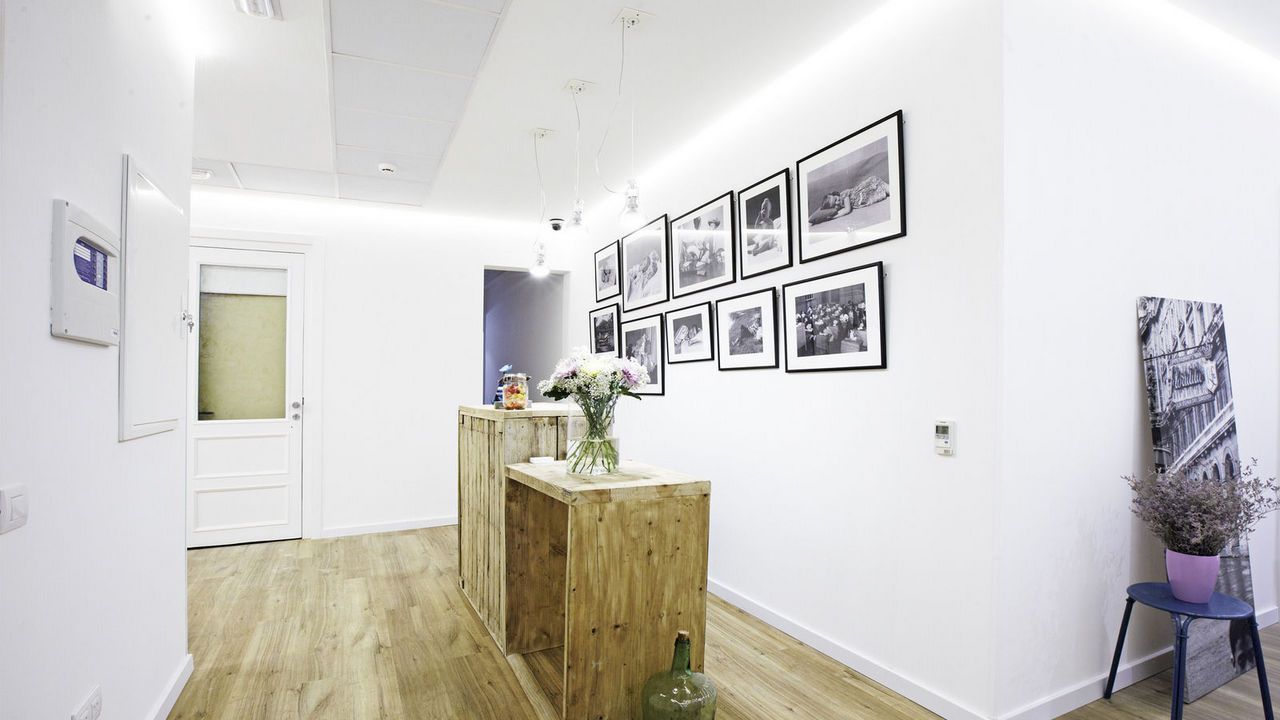 Un pasillo con una mesa de madera y cuadros en la pared.