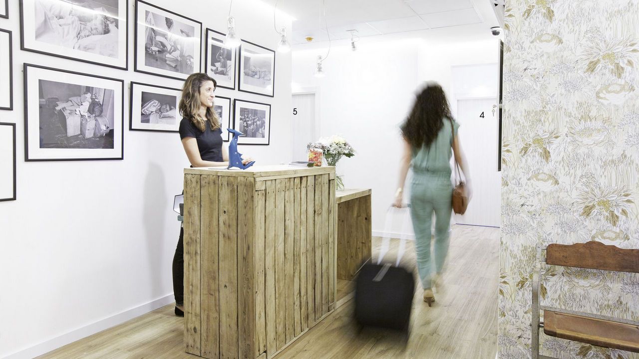 Una mujer está parada en un mostrador en una habitación con una maleta.