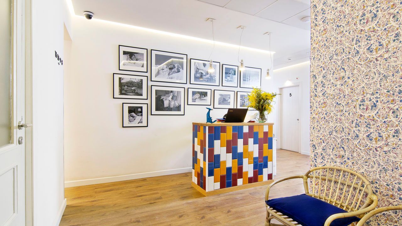 Una sala de espera con una silla de mimbre y un mostrador colorido.