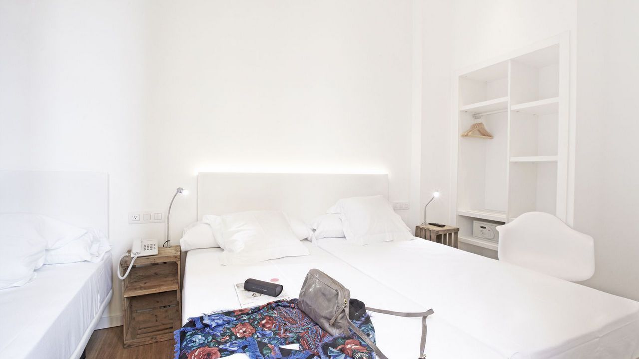 Un dormitorio con una cama grande y un ordenador portátil sobre una mesa.