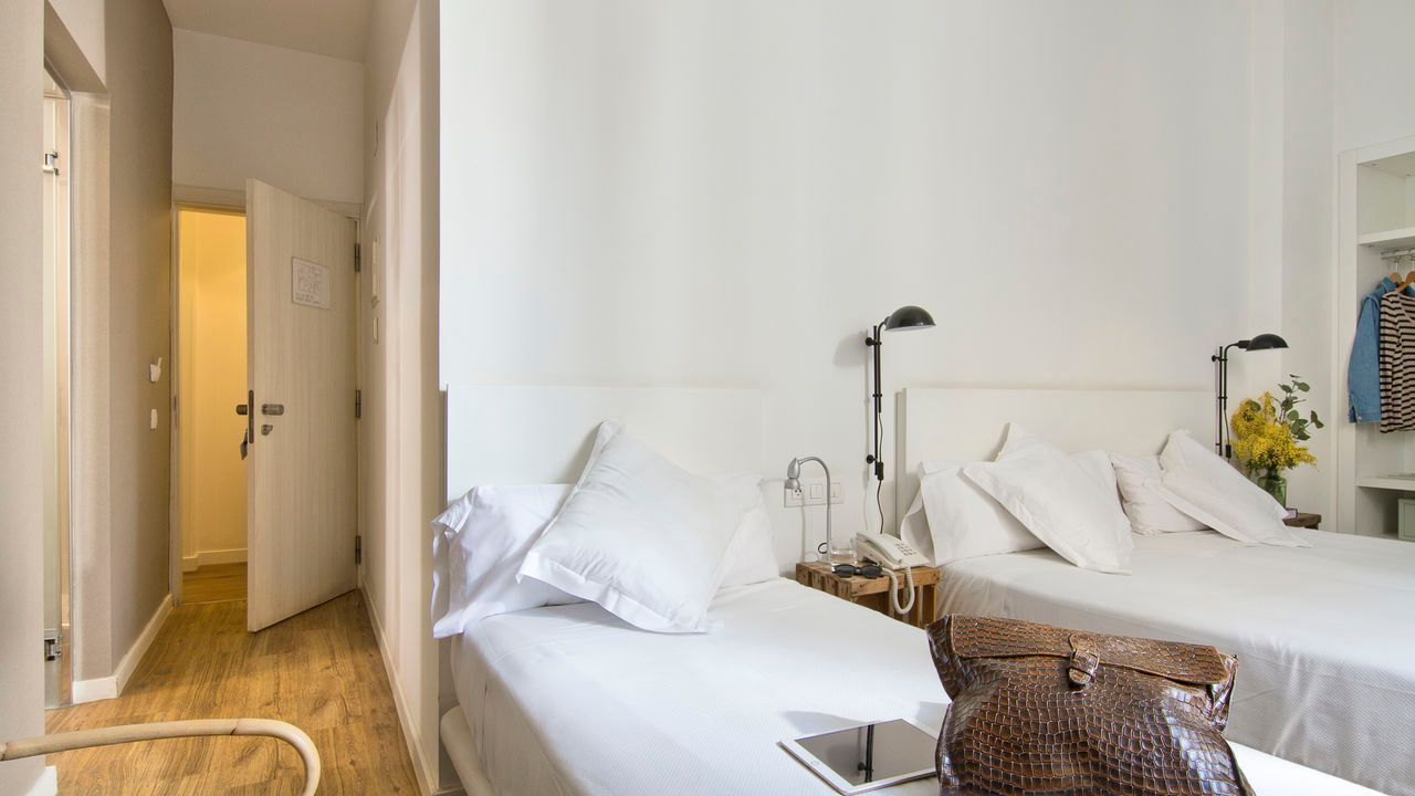 Un dormitorio con dos camas y un bolso sobre una mesa.