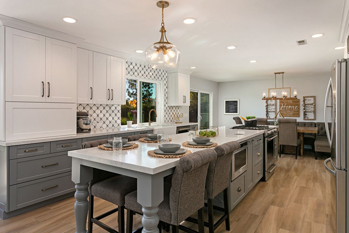 A kitchen with white cabinets and a large island in the middle.