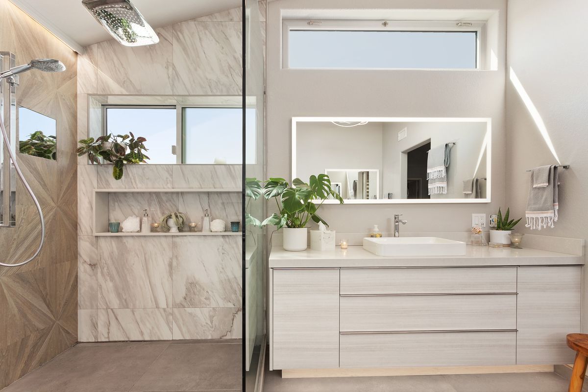 A bathroom with a walk in shower and a window.