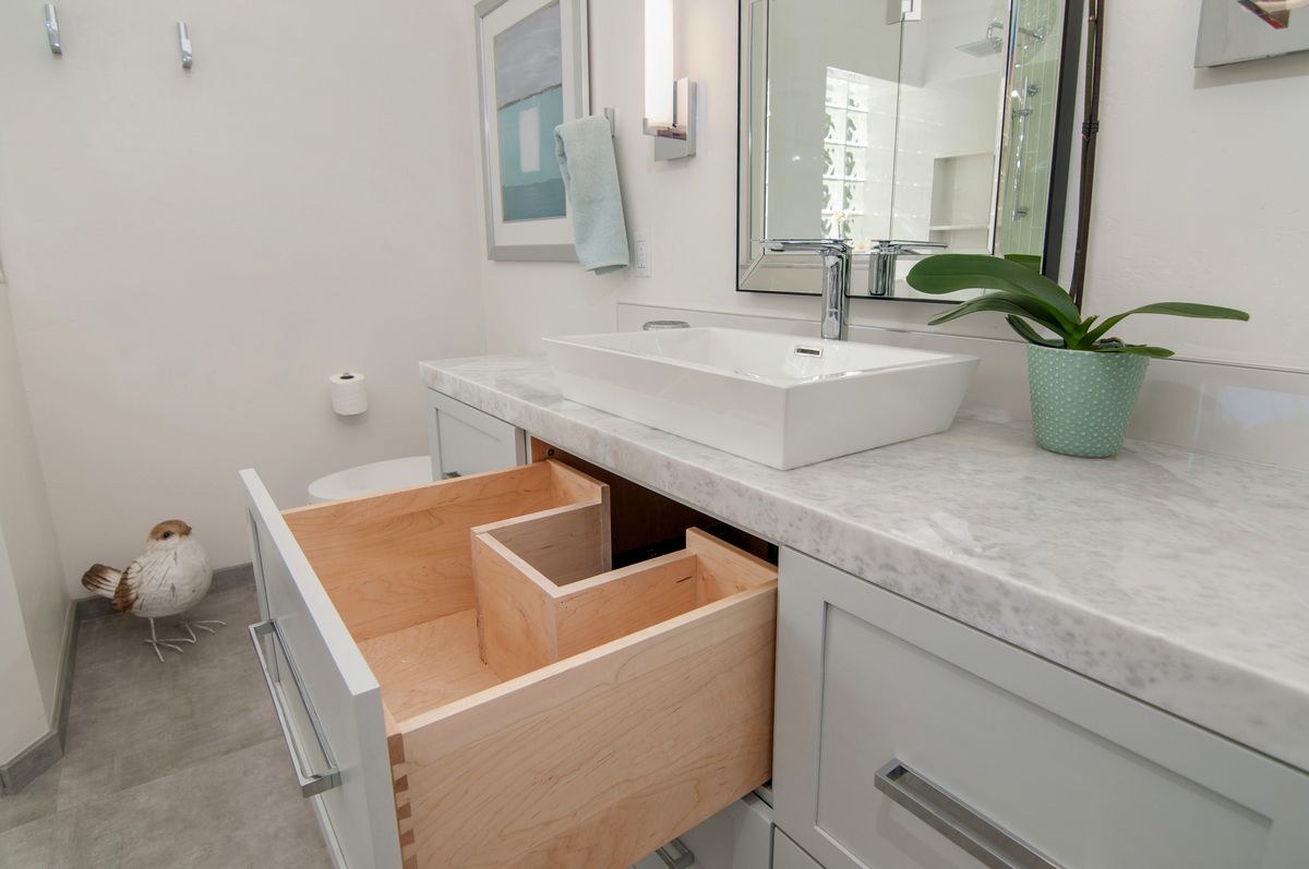A bathroom with a sink and a drawer open.