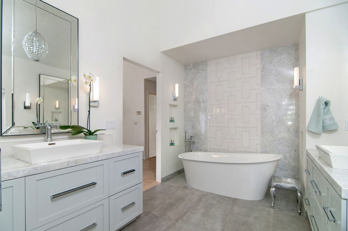 A bathroom with a tub , sink and mirror.
