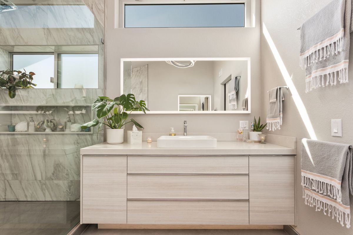 A bathroom with a sink , mirror and towels hanging on the wall.